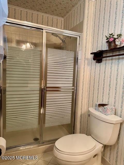 bathroom with wallpapered walls, a shower stall, toilet, and tile patterned flooring
