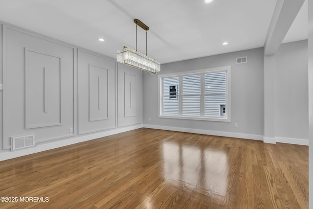 unfurnished dining area with baseboards, visible vents, wood finished floors, and recessed lighting