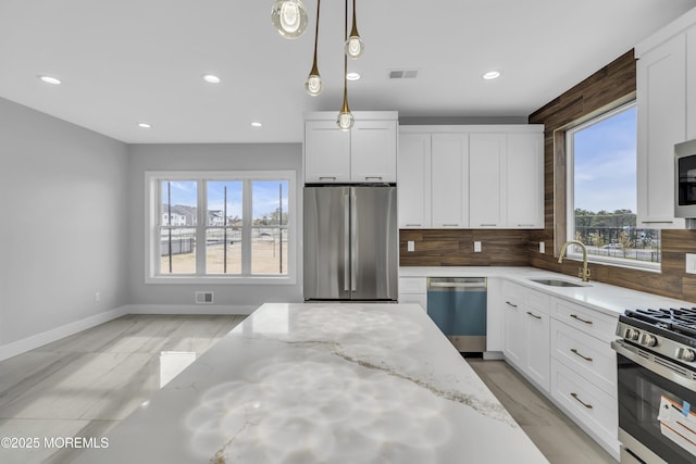 kitchen featuring recessed lighting, stainless steel appliances, decorative light fixtures, a sink, and white cabinetry