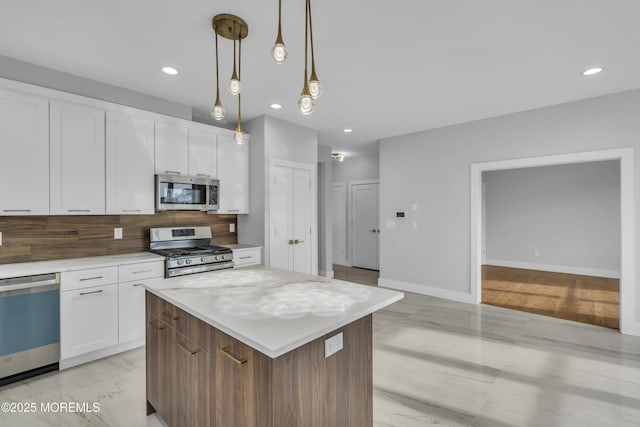 kitchen featuring recessed lighting, decorative backsplash, a kitchen island, white cabinets, and appliances with stainless steel finishes