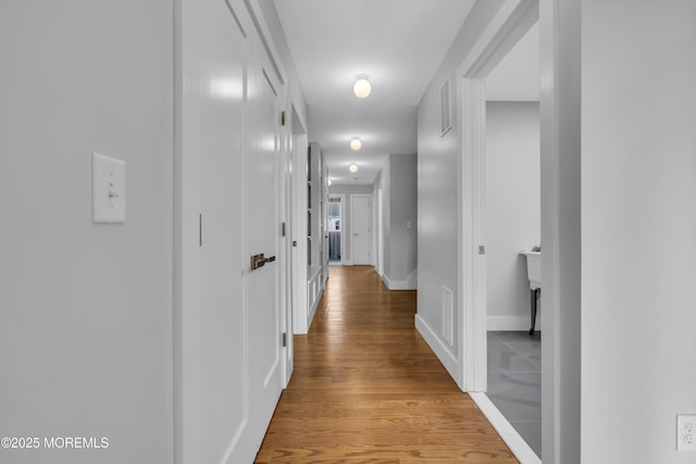 corridor featuring visible vents, light wood-style flooring, and baseboards
