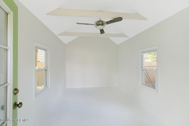 empty room featuring baseboards, ceiling fan, and vaulted ceiling with beams