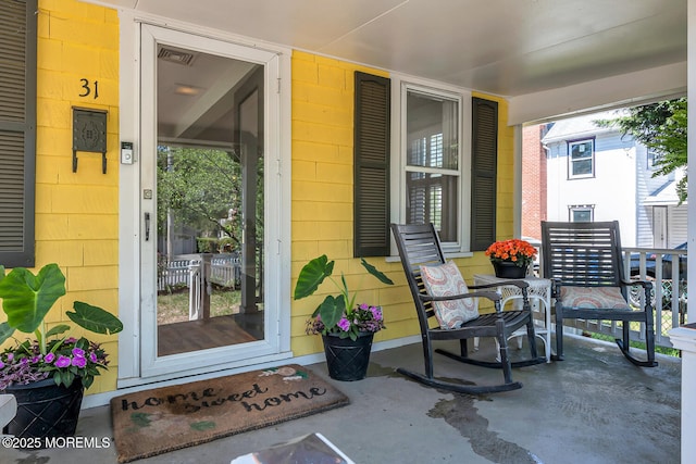 view of exterior entry with visible vents and covered porch