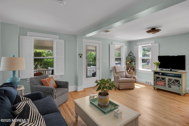 living area with baseboards, light wood-type flooring, and visible vents