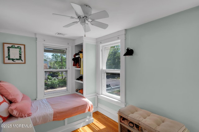 bedroom with visible vents, baseboards, ceiling fan, and wood finished floors