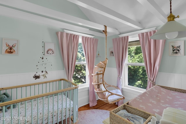 bedroom featuring wood finished floors, a wainscoted wall, and multiple windows