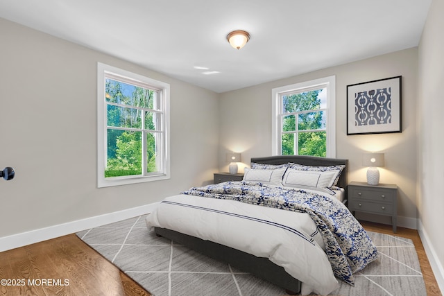 bedroom with baseboards, multiple windows, and wood finished floors