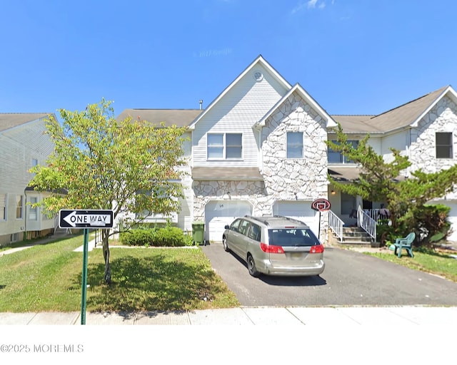 view of property with an attached garage, driveway, and stone siding