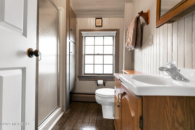 bathroom featuring a shower stall, wood finished floors, vanity, toilet, and wooden walls