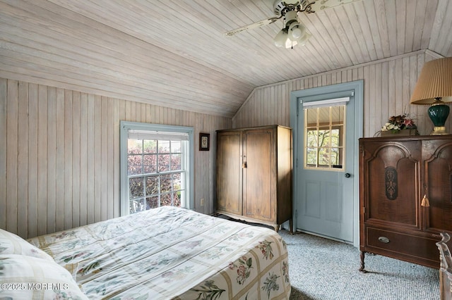 bedroom with wood walls, light colored carpet, and multiple windows
