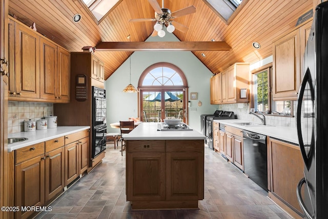 kitchen featuring vaulted ceiling with skylight, a center island, a sink, wooden ceiling, and black appliances
