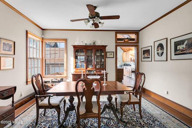 dining space with baseboards, crown molding, ceiling fan, and wood finished floors
