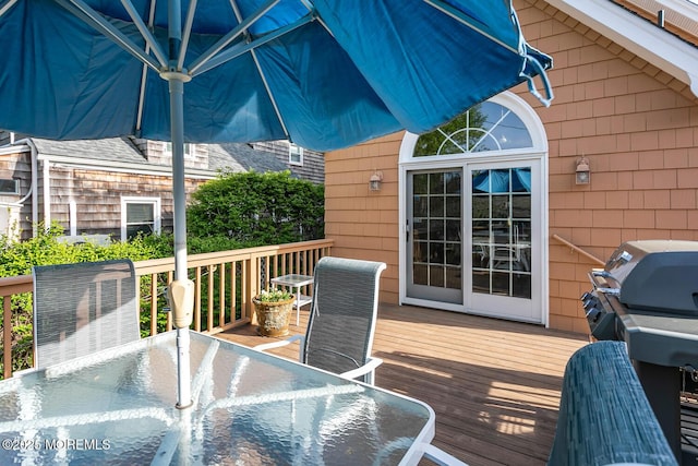wooden terrace with outdoor dining area and grilling area