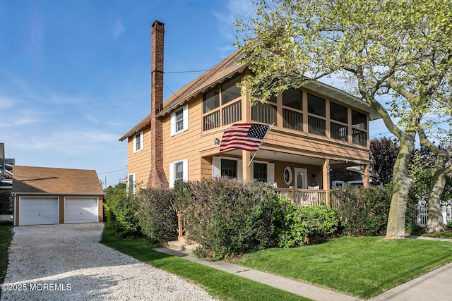 view of front of house with an outdoor structure, a porch, a front yard, and a detached garage