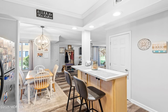 kitchen featuring a kitchen breakfast bar, crown molding, freestanding refrigerator, light wood-style floors, and recessed lighting