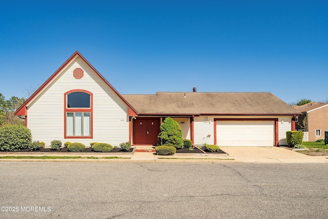 ranch-style home featuring a garage, roof with shingles, and concrete driveway