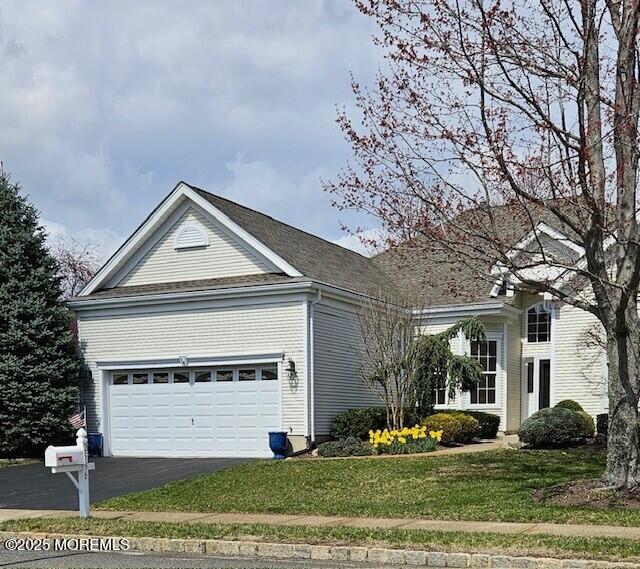 view of front of home with an attached garage, asphalt driveway, and a front yard