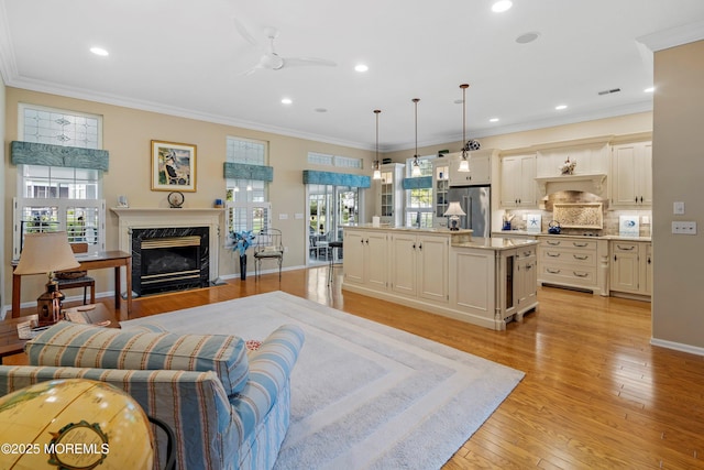 living room featuring ceiling fan, a premium fireplace, light wood-style floors, recessed lighting, and crown molding