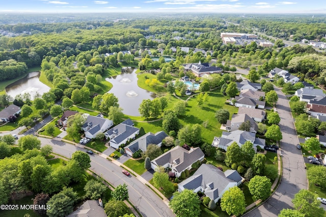 aerial view of residential area with a large body of water and a heavily wooded area