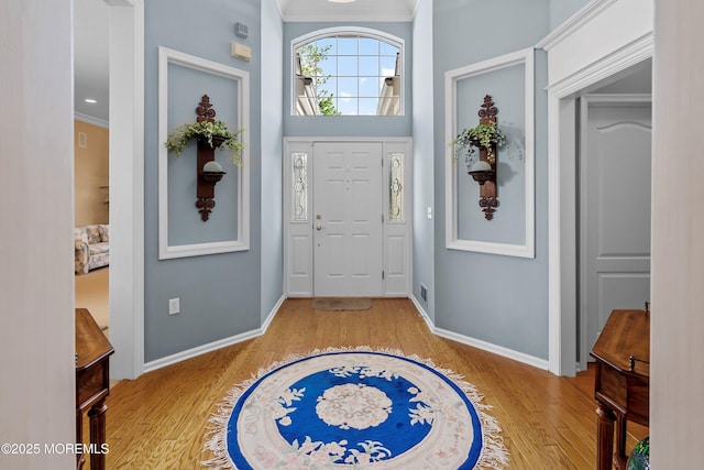 foyer entrance featuring wood finished floors, ornamental molding, and baseboards