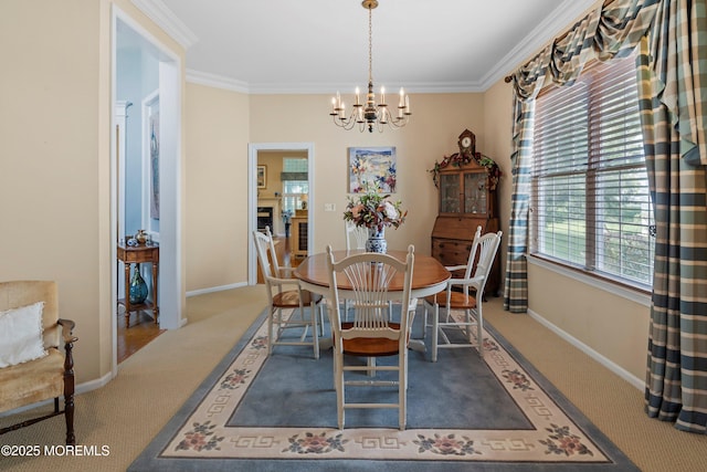 dining space with carpet, a chandelier, ornamental molding, and baseboards