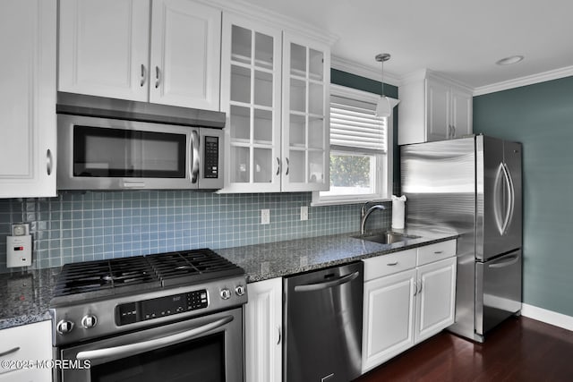 kitchen with white cabinets, a sink, dark wood finished floors, stainless steel appliances, and tasteful backsplash