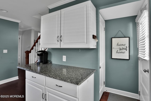 kitchen with baseboards, white cabinets, ornamental molding, and dark wood finished floors