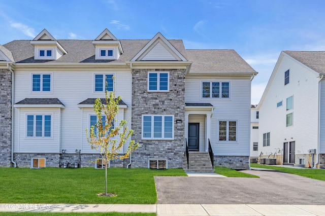 view of property featuring a front lawn, entry steps, and central AC unit