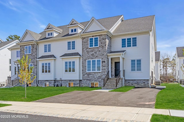 view of property with a shingled roof, cooling unit, a front yard, and stone siding