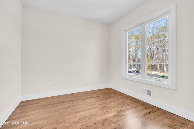 unfurnished room featuring wood finished floors, visible vents, and baseboards
