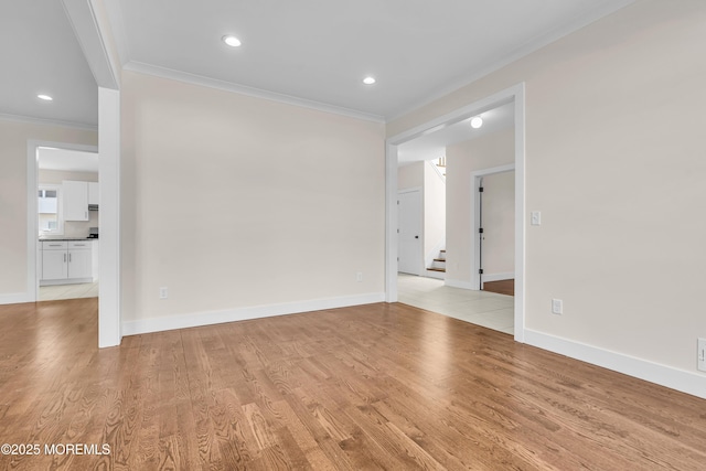 empty room featuring baseboards, stairway, light wood-style floors, and crown molding