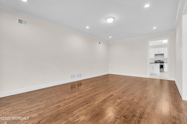 unfurnished room featuring baseboards, visible vents, ornamental molding, and wood finished floors