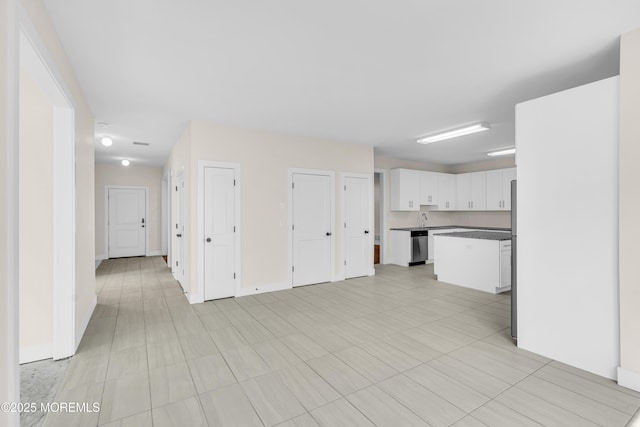 unfurnished living room featuring a sink and baseboards