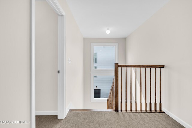 hall featuring an upstairs landing, carpet flooring, and baseboards