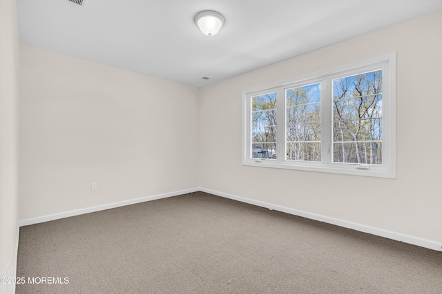 carpeted spare room featuring baseboards