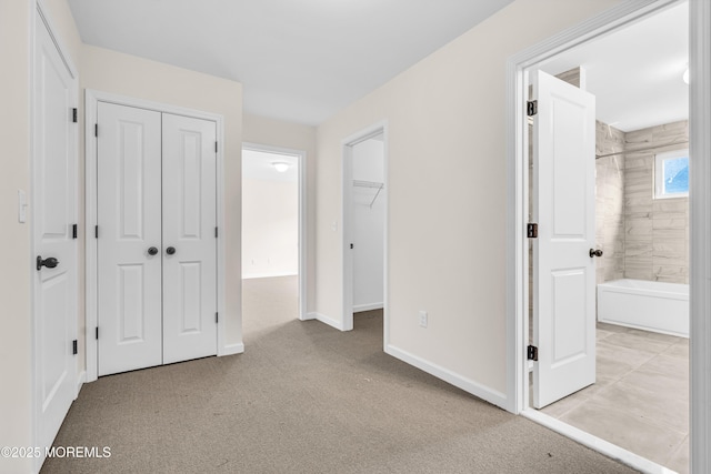 unfurnished bedroom featuring multiple closets, baseboards, carpet, and ensuite bathroom