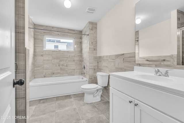 full bath featuring visible vents, toilet, tile walls, vanity, and bathtub / shower combination