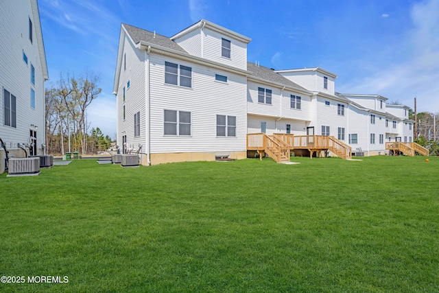 rear view of property featuring a lawn, a wooden deck, stairway, and central AC