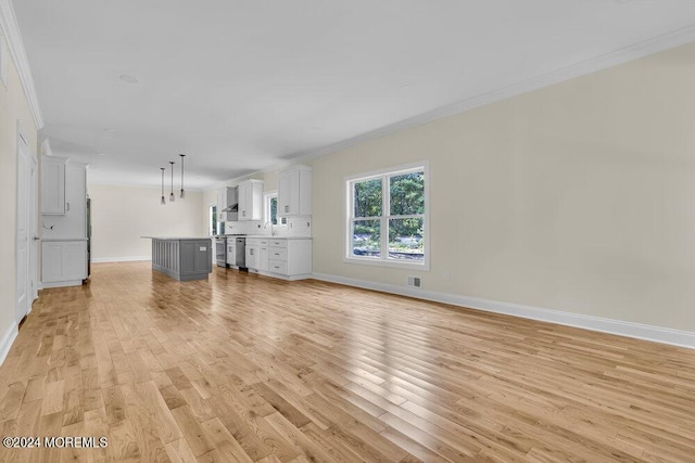 unfurnished living room with crown molding, baseboards, light wood-style flooring, and a sink