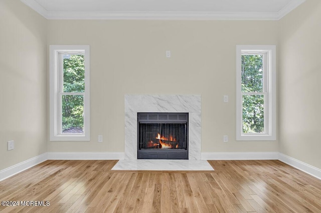 unfurnished living room with crown molding, baseboards, wood finished floors, and a high end fireplace