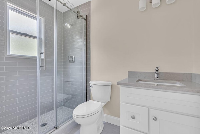 full bath featuring vanity, baseboards, a shower stall, and toilet