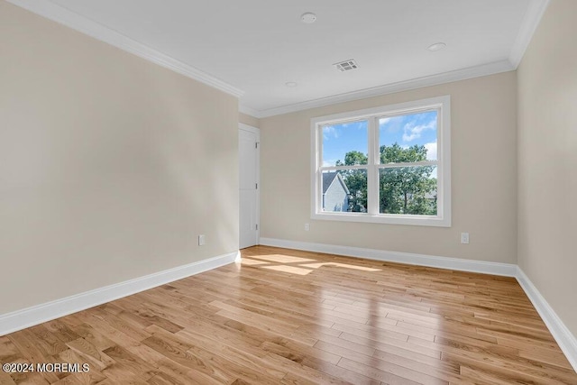 unfurnished room featuring baseboards, ornamental molding, light wood-style flooring, and visible vents