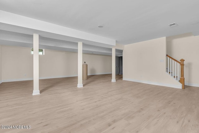 finished basement featuring stairway, baseboards, light wood finished floors, and visible vents