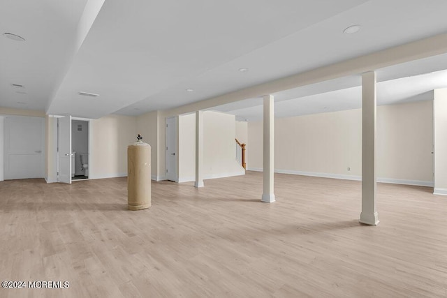 finished below grade area with baseboards, stairway, and light wood-style floors