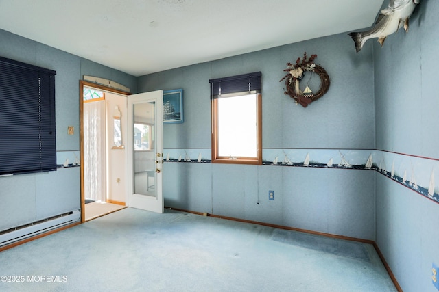 carpeted spare room with a wealth of natural light, french doors, and a baseboard heating unit