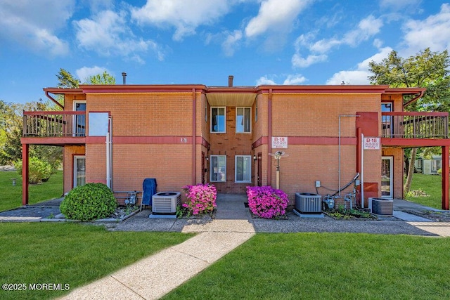 back of house featuring a yard, brick siding, and central AC unit