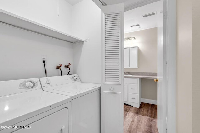 laundry area featuring laundry area, independent washer and dryer, visible vents, a sink, and light wood-style flooring