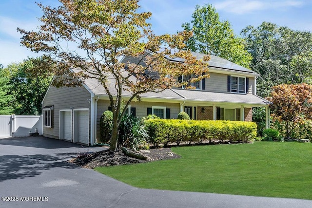 view of front of property with solar panels, a front yard, a garage, fence, and aphalt driveway