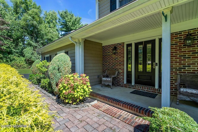 property entrance with brick siding and covered porch
