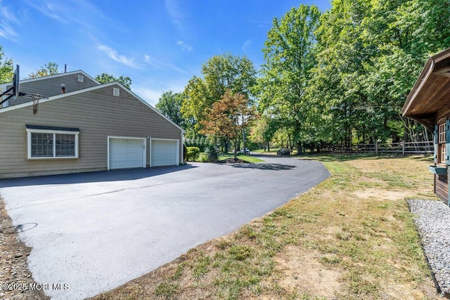 view of side of property featuring fence, an attached garage, and driveway